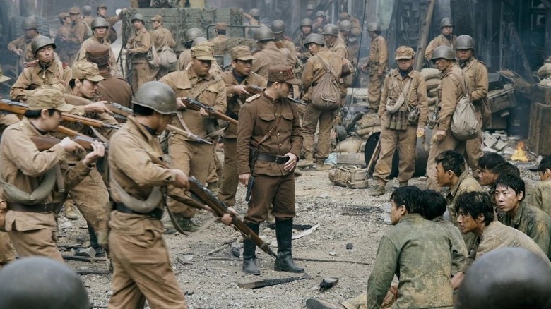 A group of soldiers aim rifles at huddled prisoners in The Front Line (2011)
