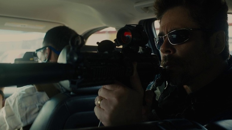 Alejandro Gillick (Benicio Del Toro) pointing his gun from inside a car in Sicario