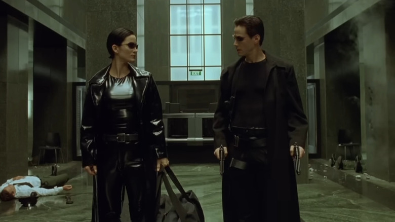 Neo (Keanu Reeves) and Trinity (Carrie-Anne Moss) looking at each other in hotel lobby in The Matrix