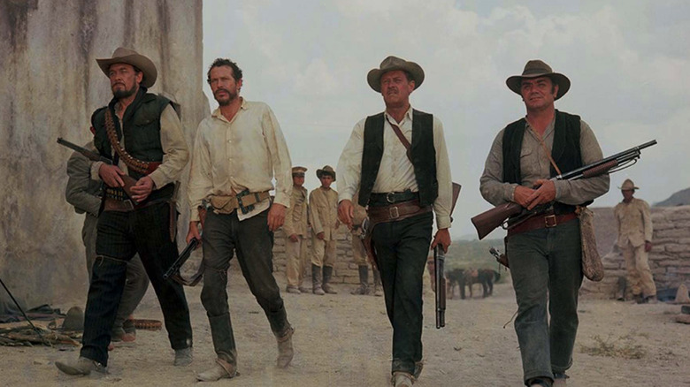 Outlaws walking through the desert holding guns in The Wild Bunch