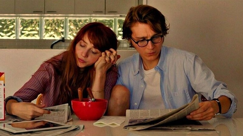 Ruby Sparks (Zoe Kazan) and Calvin Weir-Fields hold hands while reading the newspaper in Ruby Sparks