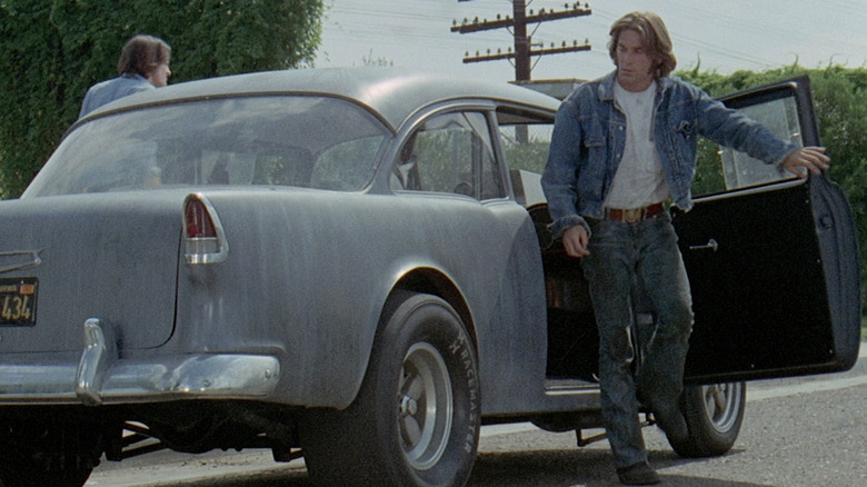 The Mechanic (Dennis Wilson) steps out of a car in Two-Lane Blacktop