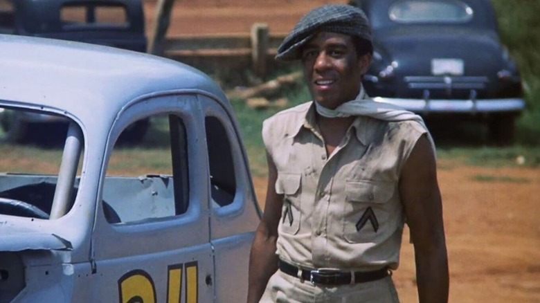 Wendell Scott (Richard Pryor) walks by a stock car in Greased Lightning