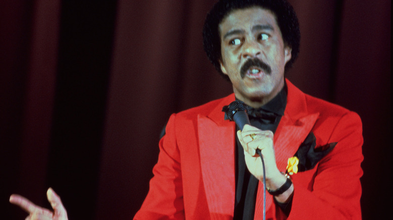 Richard Pryor holds a mic on stage while wearing a bright red suit in Richard Pryor: Live on the Sunset Strip