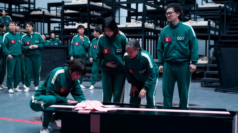 Park Sung-hoon's Cho Hyun-ju examining a black coffin on Squid Game