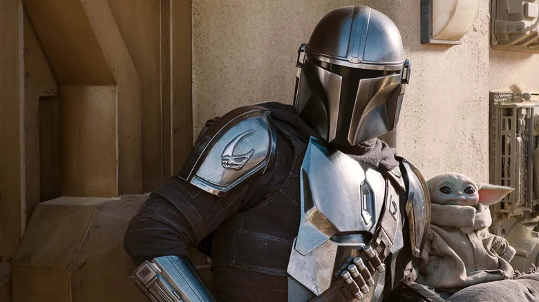 Din Djarin (Pedro Pascal) and Grogu stand ready for action in an alley in The Mandalorian