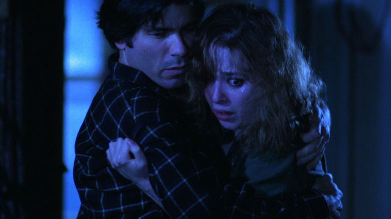 Tom Nardini as Horatio and Brenda Bazinet as Barbara, hugging in shock in Siege