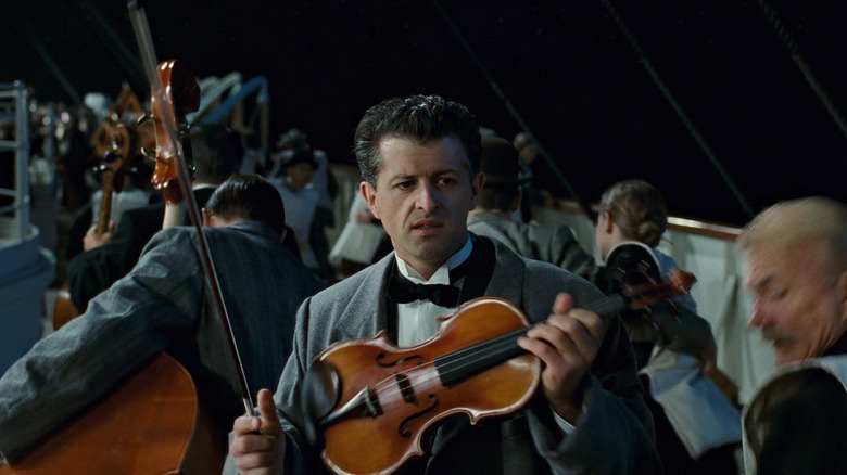 Man holding violin on deck in Titanic