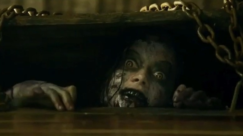 a possessed Mia (Jane Levy) peering out from a chained-shut trapdoor in The Evil Dead