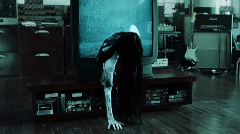 Samara (Daveigh Chase) crawling out of a static-filled television, her hand on the floor