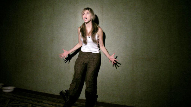 A woman screams in darkness.