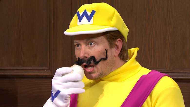 Elon Musk dressed as Wario eating garlic on Saturday Night Live