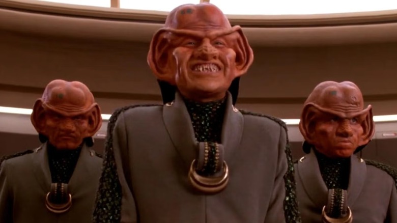 One grinning and two snarling Ferengi on the bridge of the Enterprise, in Ferengi wealthy wear, on Star Trek the Next Generation