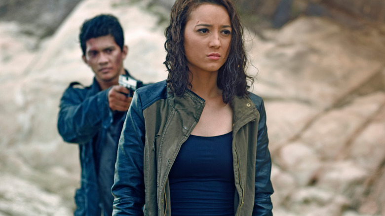 Iko Uwais points a gun at a woman