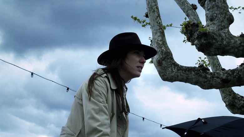 Zoé Bruneau as Ivitch wearing a black hat and sitting under dark clouds in Goodbye to Language