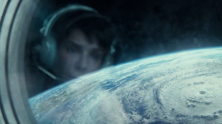 Sandra Bullock as Dr. Ryan Stone looking out at the Earth through a space station window in Gravity