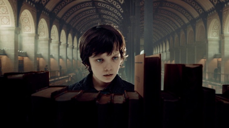 Asa Butterfield as Hugo Cabret looking at books in a library in Hugo
