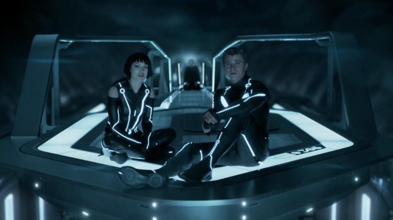 Olivia Wilde as Quorra and Garrett Hedlund as Sam Flynn sitting on a neon-lit floor in TRON: Legacy