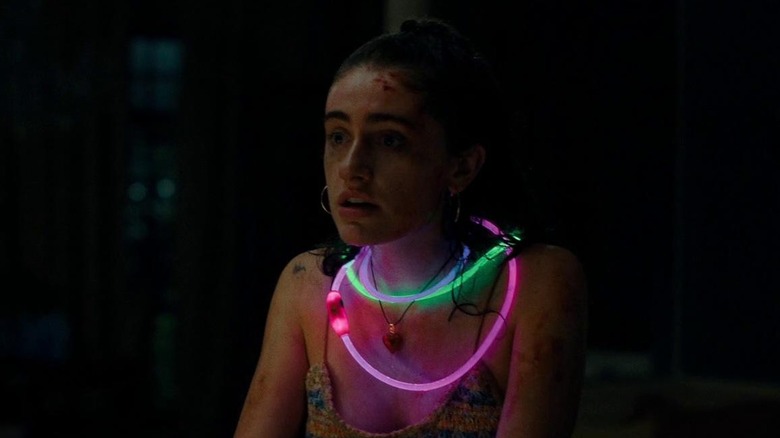 Rachel Sennott as Alice in Bodies Bodies Bodies, bloodied and wearing several glowing necklaces