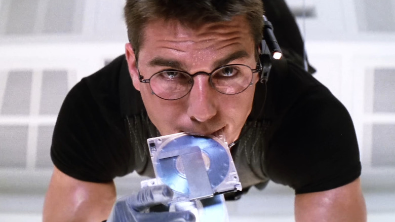 Tom Cruise as Ethan Hunt, hanging from the ceiling and biting down on a disk in Mission: Impossible