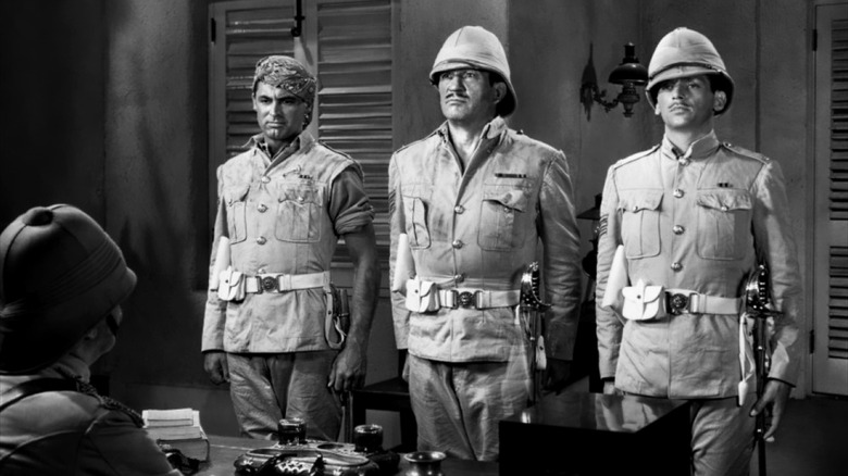 Archibald Cutter (Cary Grant), MacChesney (Victor McLaglen), and Tommy Ballantine (Douglas Fairbanks, Jr.) stand at attention before an officer in Gunga Din