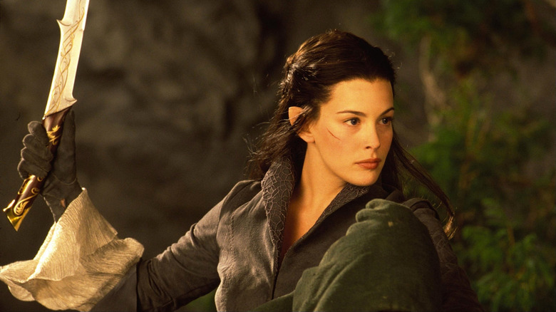 Arwen (Liv Tyler) holds up a sword while on horseback in The Lord of the Rings: The Fellowship of the Ring