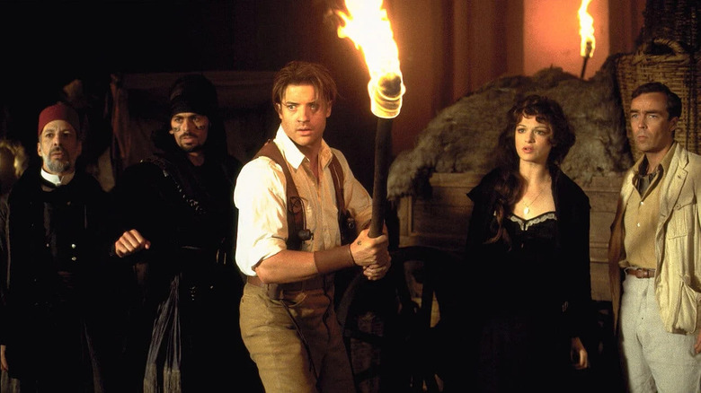 Rick O'Connell (Brendan Fraser) holds a torch in front of Terence Bey (Erick Avari), Ardeth Bey (Oded Fehr), Evie Carnahan (Rachel Weisz), and Jonathan Carnahan (John Hannah) in The Mummy (1999)
