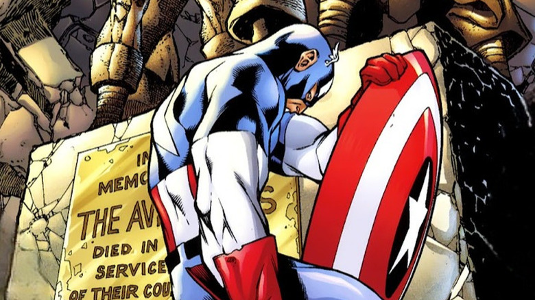 Captain America kneels in front of a statue of the Avengers