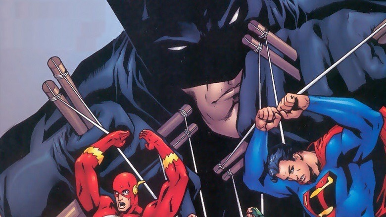 Batman playing with puppets of Flash and Superman