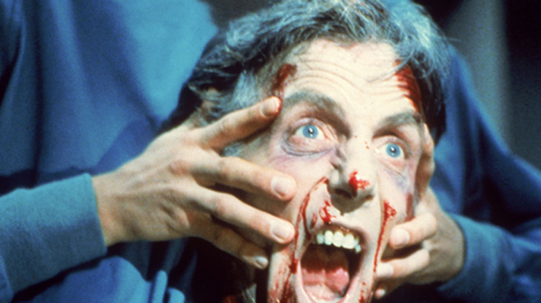 man holds decapitated head in Re-Animator