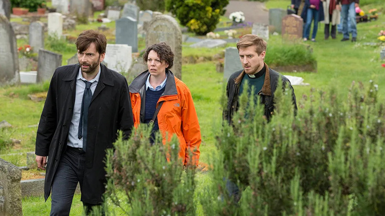 Alec Hardy (David Tennant), Ellie Miller (Olivia Colman), and Paul Coates (Arthur Darvill) walk through a graveyard in Broadchurch