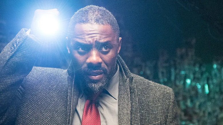 John Luther (Idris Elba) shines a flashlight outside at night in Luther