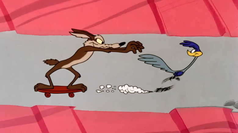 Wile E. Coyote riding a skateboard and trying to catch the Road Runner in Looney Tunes