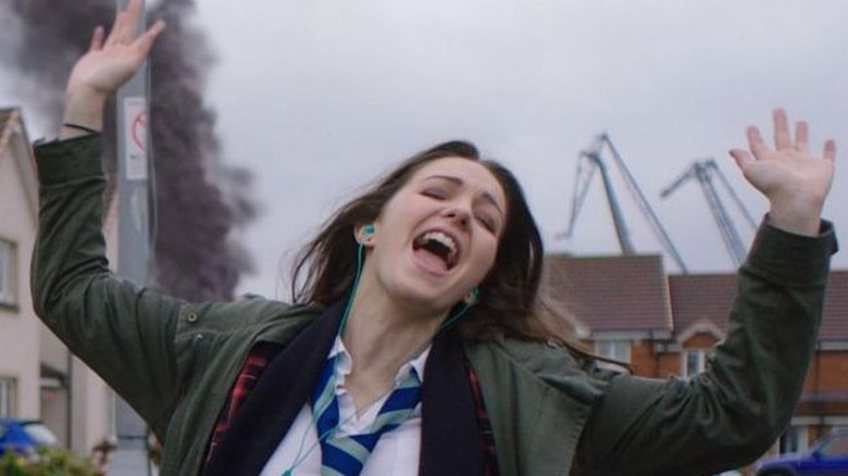 Anna singing with earbuds in front of billowing smoke