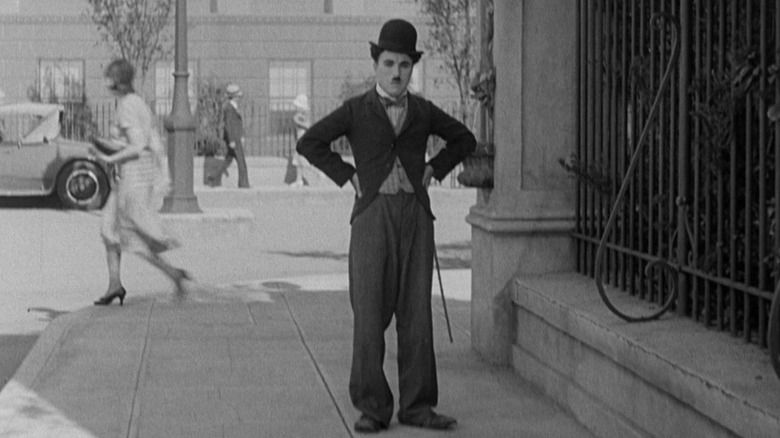 Lone Prospector (Charlie Chaplin) stands on a street corner in City Lights