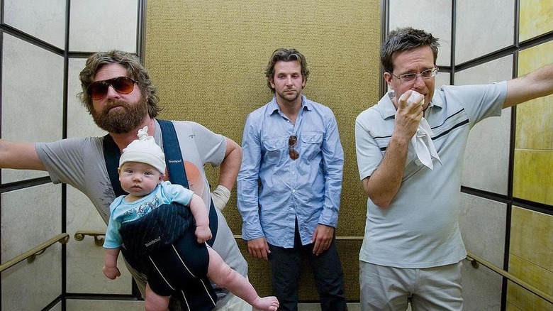 Zach Galifianakis as Alan holds a baby in an elevator next to Bradley Cooper as Phil and Ed Helms as Stu in The Hangover