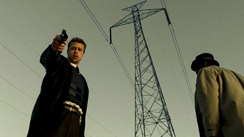 David Mills (Brad Pitt) points a pistol downward while distraught under power lines next to William Somerset (Morgan Freeman) in Seven (1995)