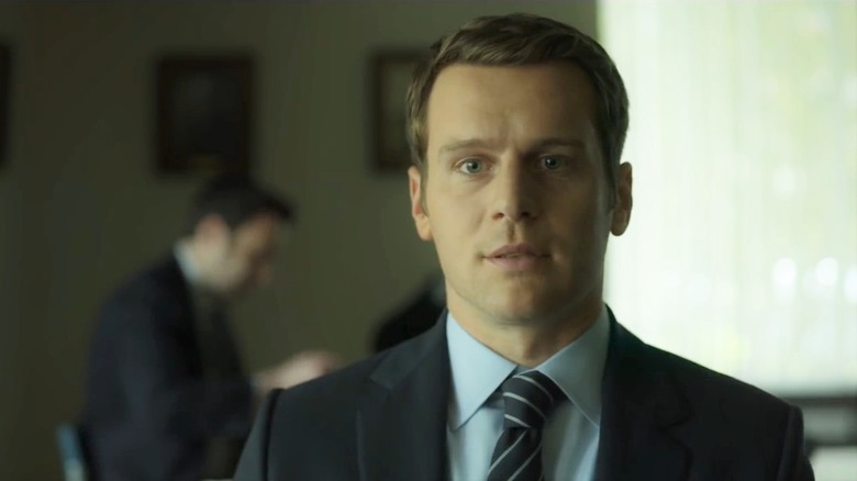 Holden Ford (Jonathan Groff) stands in a living room in Mindhunter