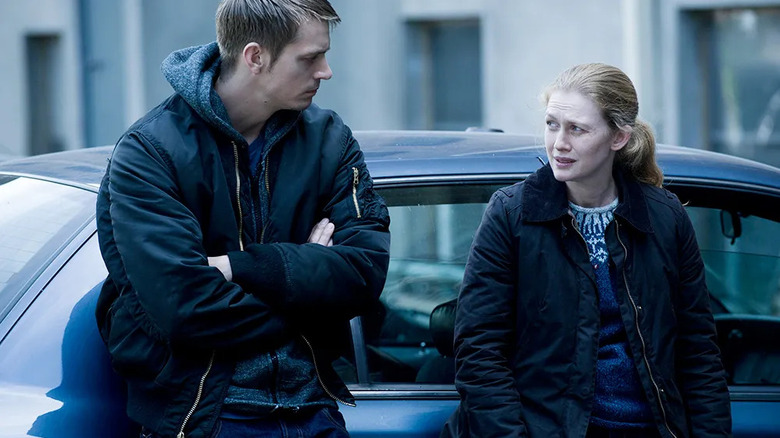 Stephen Holder (Joel Kinnaman) and Sarah Linden (Mireille Enos) speak to each other while leaning on a car in The Killing
