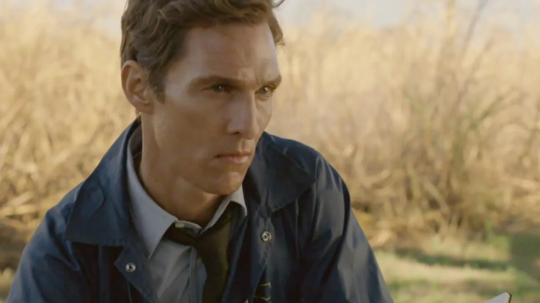 Rust Cohle (Matthew McConaughey) stares intently at an exterior crime scene in True Detective