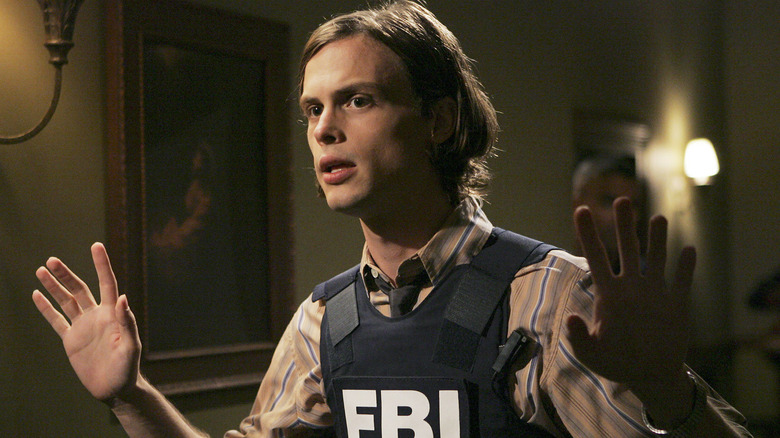 Matthew Gray Gubler as Spencer Reid, holding his hands in the air on Criminal Minds