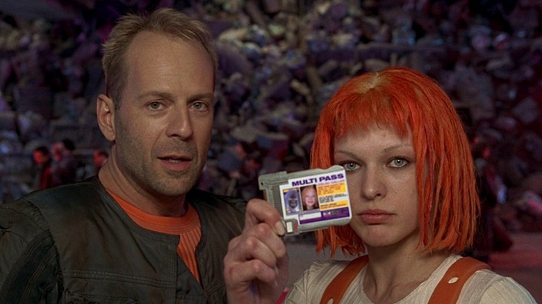 Korben Dallas (Bruce Willis) stands next to Leeloo (Milla Jovovich) holding her multiplass in The Fifth Element