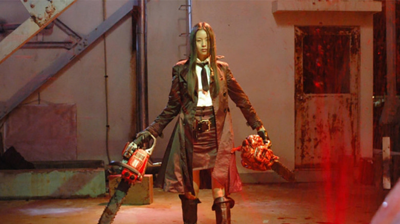 Eihi Shiina as Ruka holding two chainsaws as blood spurts out of a victim in front of her in Tokyo Gore Police