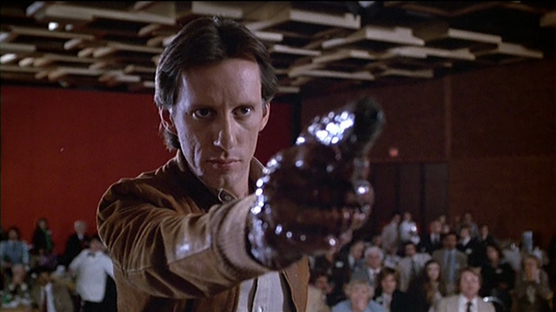 Max Renn (James Woods) points a gun in front of a crowd in Videodrome