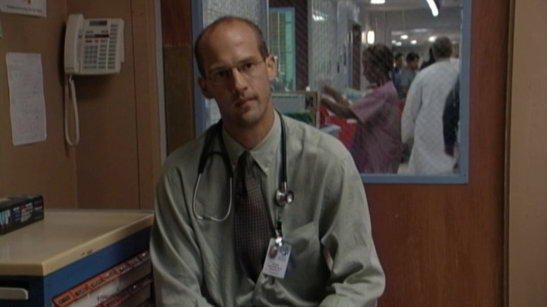 Anthony Edwards as Dr. Mark Greene sitting in hospital room in ER