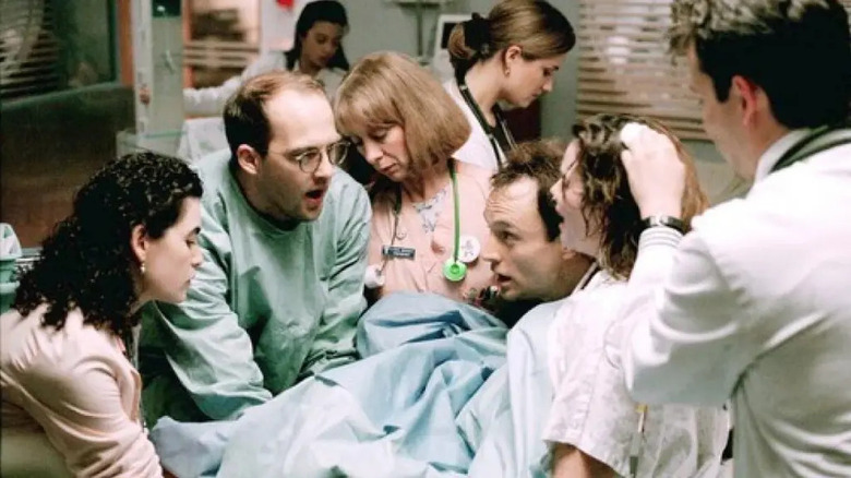 Doctors and nurses played by Juliana Margulies, Anthony Edwards, Sherry Springfield, and Noah Wyle surrounding Colleen Flynn playing women in childbirth and Bradley Whitford as her husband in ER