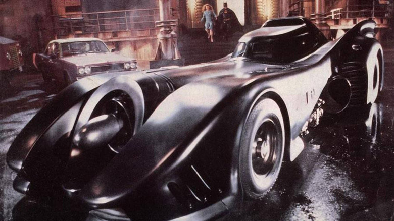 Batman (Michael Keaton) and Vicki Vale (Kim Basinger) approach the parked Batmobile in Batman (1989)