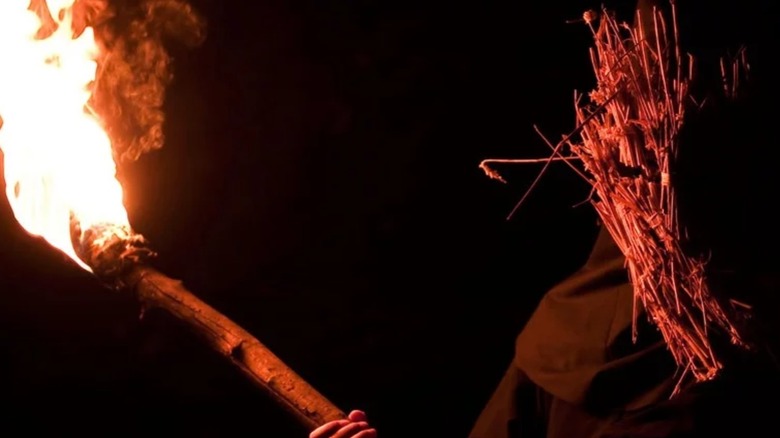 Man wearing mask and holding torch