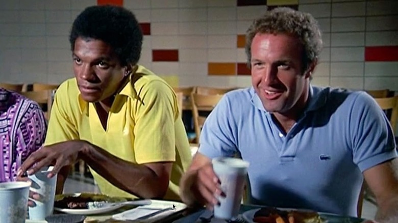 Gale Sayers (Billy Dee Williams) and Brian Piccolo (James Caan) sit together at a lunch cafeteria table in Brian's Song