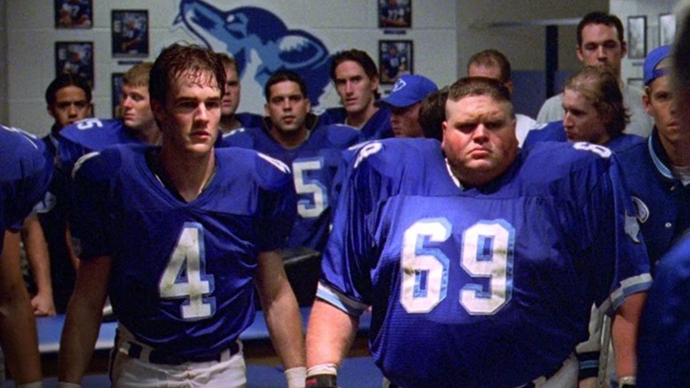 Jonathan Moxon (James Van Der Beek) and Billy Bob (Ron Lester) stand sweaty with their team in the locker room in Varsity Blues